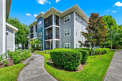 A modern apartment building with a well-maintained lawn and walkway.