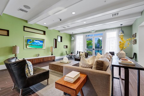 A living room with a green wall and a painting of a beach scene.