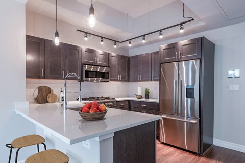 A modern kitchen with a stainless steel refrigerator and wooden bar stools.