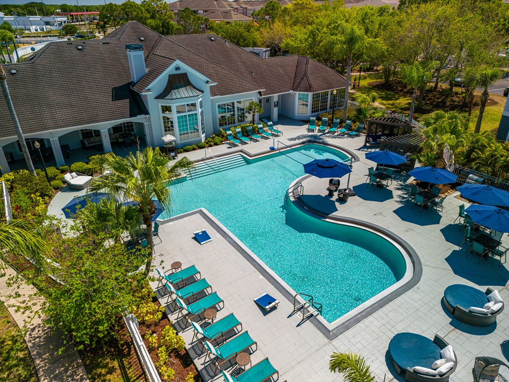 an aerial view of the resort style pool with lounge chairs and umbrellas