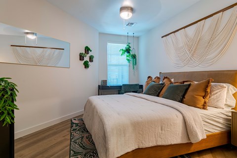 A bedroom with a large bed and a hanging plant.