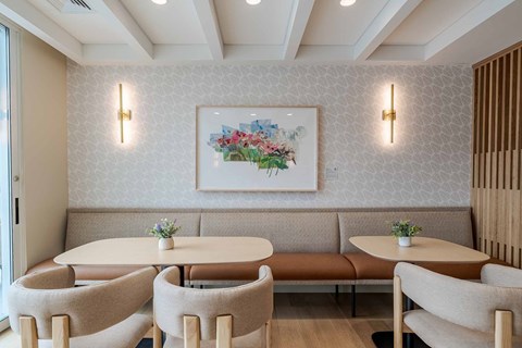 A dining area with a floral picture on the wall and a bench seating two people.
