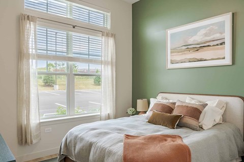 A bedroom with a large bed and a painting of a beach scene on the wall.