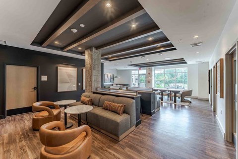 A modern living room with a grey sofa and wooden chairs.