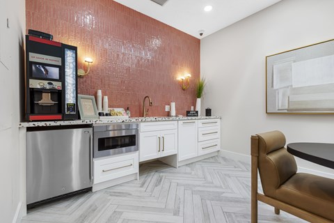 A modern kitchen with a stainless steel refrigerator and oven, white cabinets, and a herringbone patterned floor.