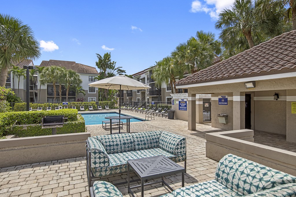 a patio with couches and tables and a pool in the background