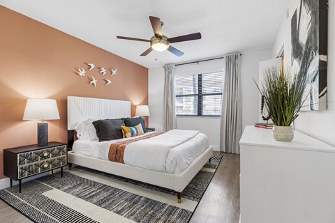 A bedroom with a white bed and a ceiling fan.