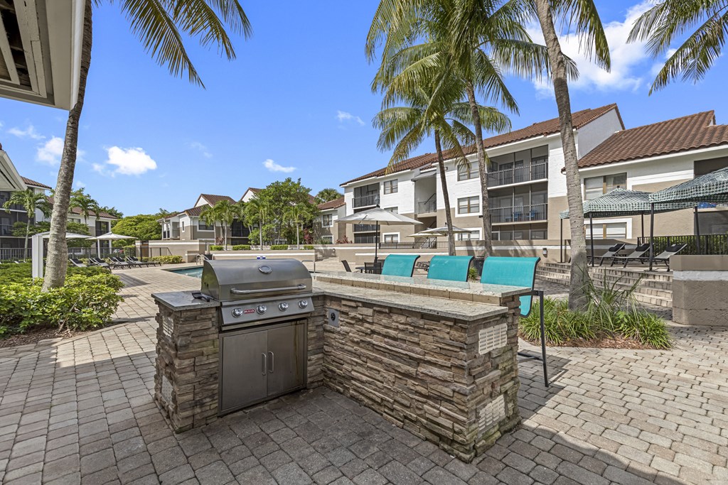 an outdoor kitchen with a grill and a table and chairs