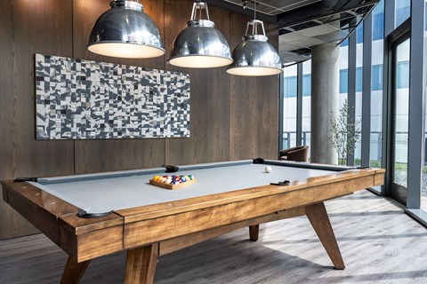 A pool table with a wooden frame and a green felt cloth is in the foreground of the image.