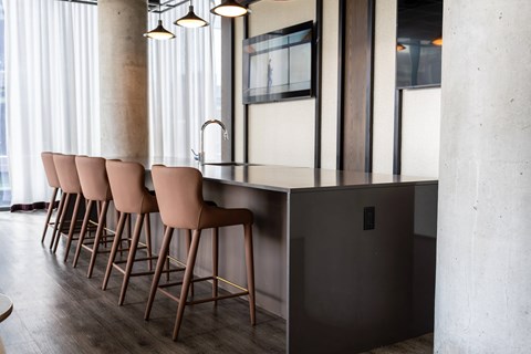 A row of brown bar stools are lined up in front of a dark brown bar.