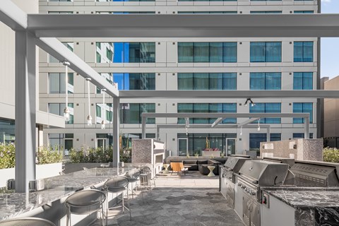 A modern building with a glass facade and a patio area with chairs and tables.