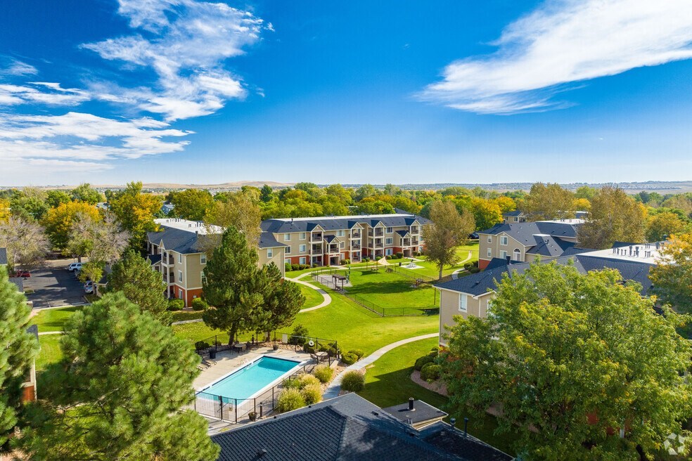 an aerial view of an apartment complex with a green lawn and a pool