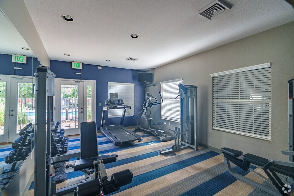 a gym with weights and cardio machines and a window