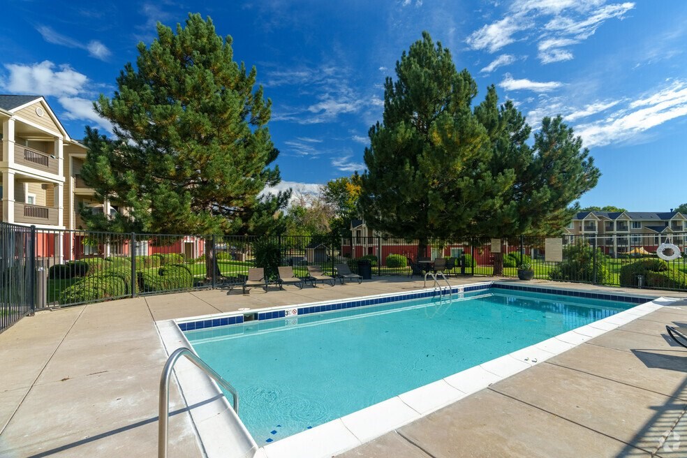 a swimming pool with trees and a building in the background