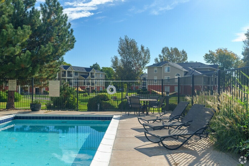 a swimming pool with lounge chairs next to a fence