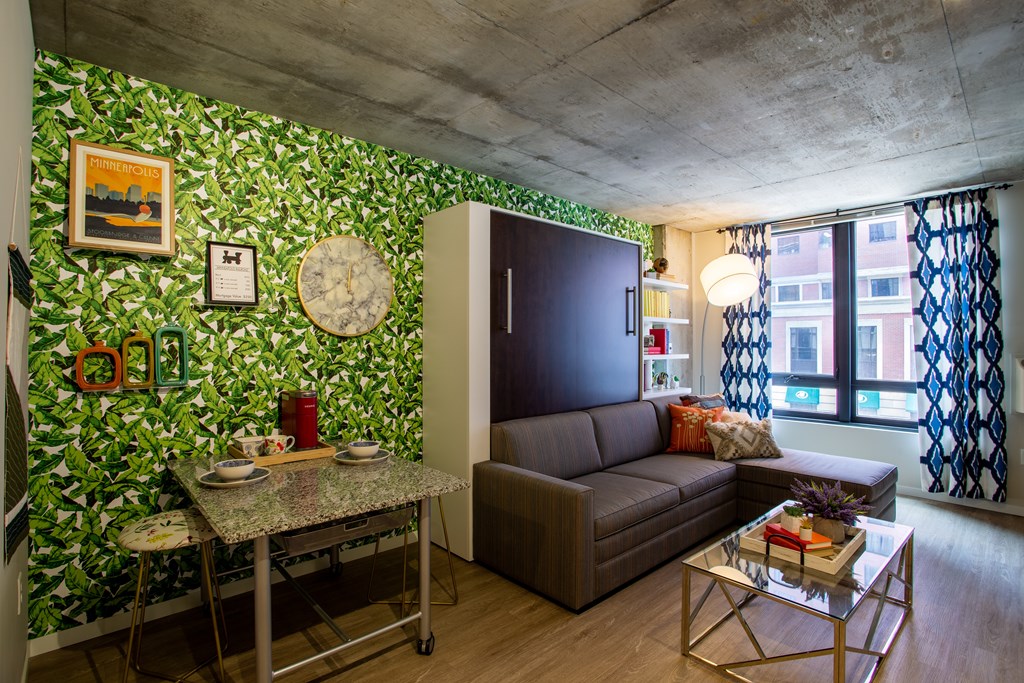 a living room with green wallpaper and a brown couch