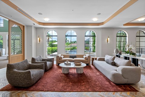 A large, modern living room with a red rug and a coffee table in the center.