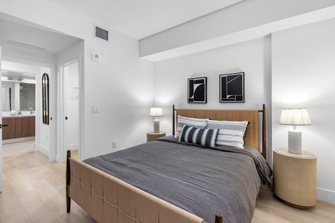 A bedroom with a large bed and two lamps.