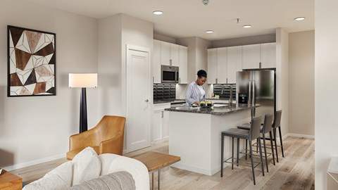 A man is standing in a kitchen with a counter and a chair.