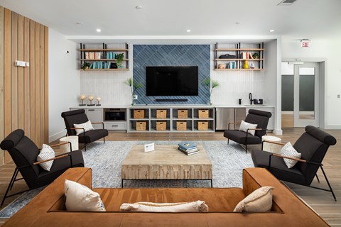A living room with a wooden floor and a large television on the wall.