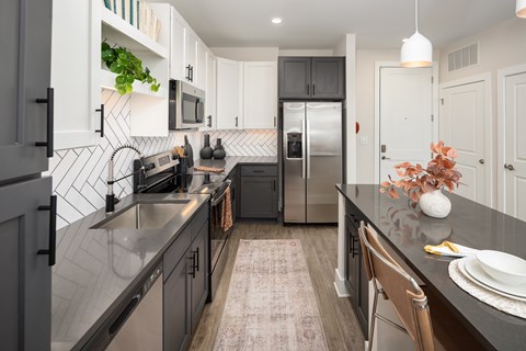 A kitchen with a black counter top and stainless steel appliances.