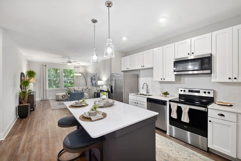 an open kitchen and dining room with white cabinets and stainless steel appliances