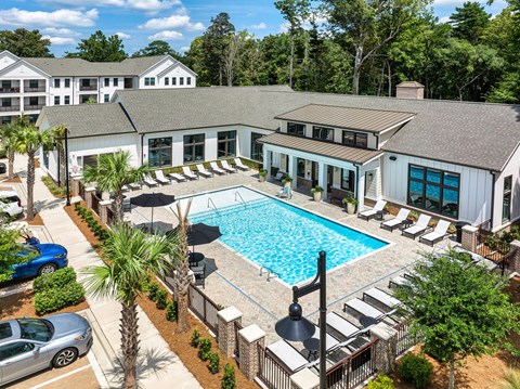 an aerial view of a swimming pool in front of a building with a pool house