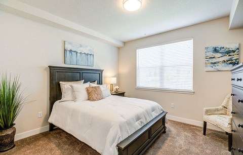 A bedroom with a large bed and a chair.