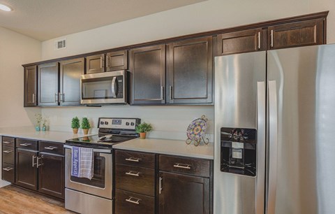 A kitchen with a stainless steel refrigerator and black cabinets.