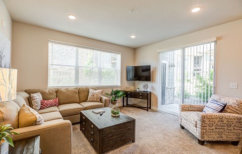 A living room with a tan couch and a brown coffee table.