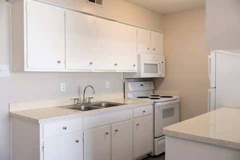 A kitchen with white cabinets and appliances.