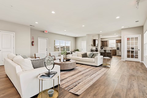 A spacious living room with white furniture and a wooden floor.