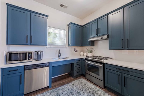 A kitchen with dark blue cabinets and stainless steel appliances.