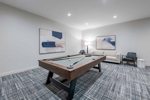 A room with a pool table and two chairs.