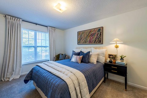 A bedroom with a large bed and a window with curtains.