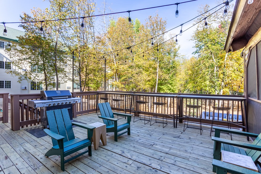 a deck with a picnic table and chairs and a grill