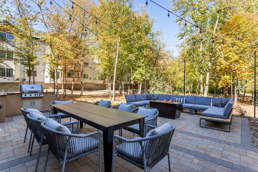 a patio with couches tables and chairs and trees