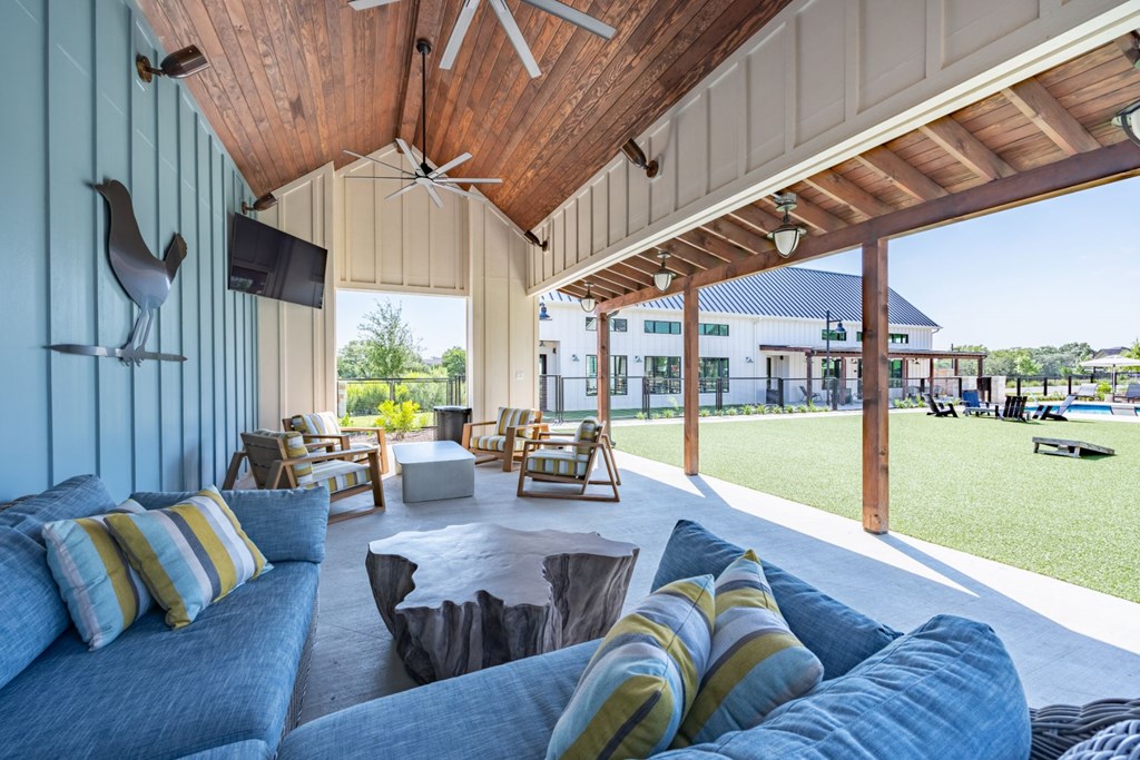 a covered patio with couches and chairs and a tv on the wall