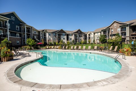 A swimming pool surrounded by a fence and chairs.