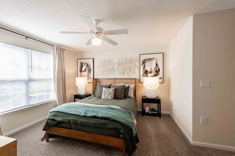 A bedroom with a bed, two lamps, and a ceiling fan.