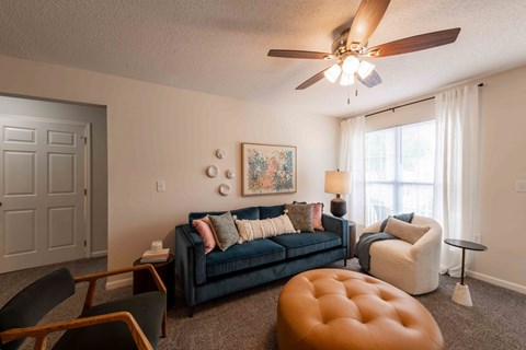 A living room with a blue couch and a brown ottoman.