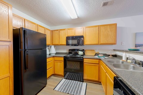 A kitchen with wooden cabinets and a black refrigerator.