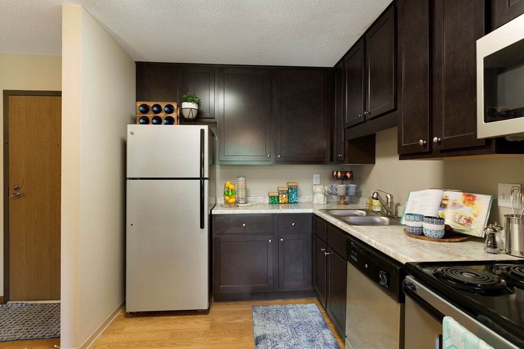 a kitchen with black cabinets and a stainless steel refrigerator