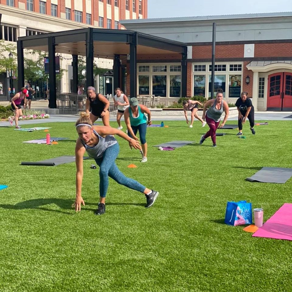 a group of people doing yoga on a lawn in front of a building