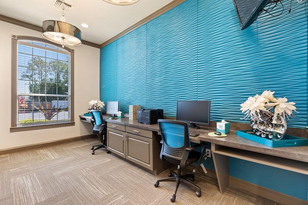 two computers on a long desk with a large window in the background