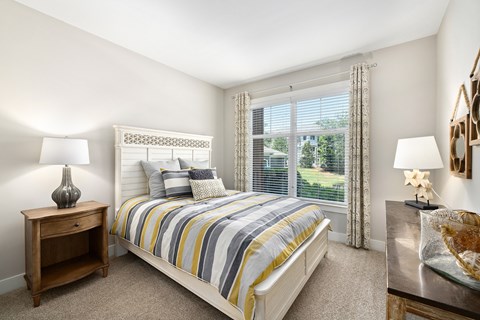 A bedroom with a bed, nightstand, and window.
