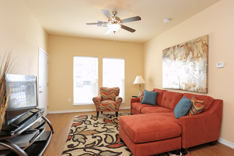 A living room with a red couch and a ceiling fan.