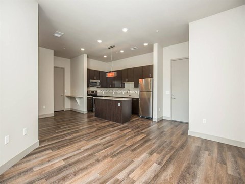 an empty living room and kitchen with wood flooring
