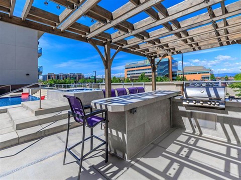 a patio with a grill and a table with chairs