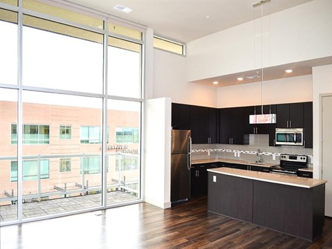 an empty kitchen with black cabinets and a large window